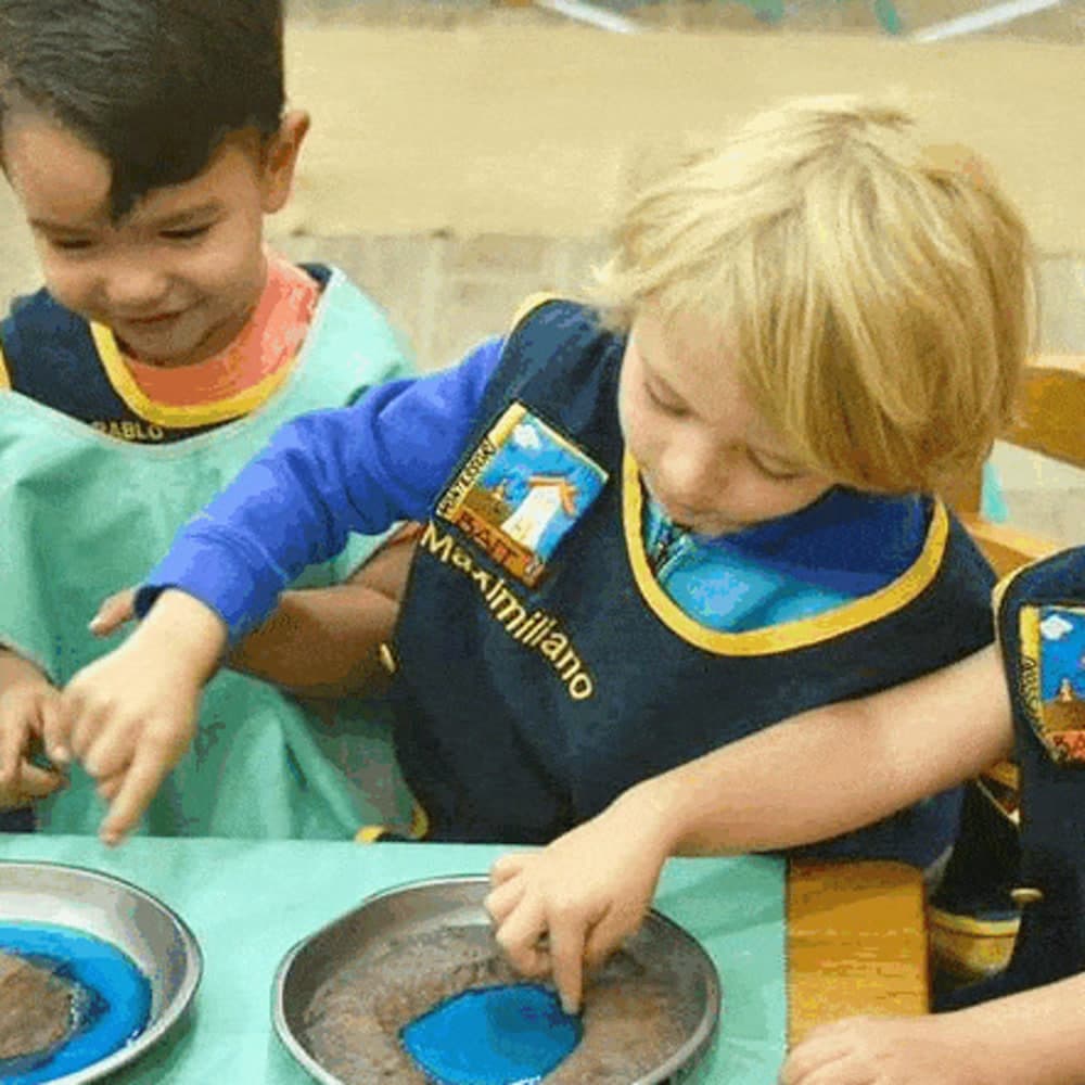 Dos niños trabajando juntos con charolas en la misma mesa
