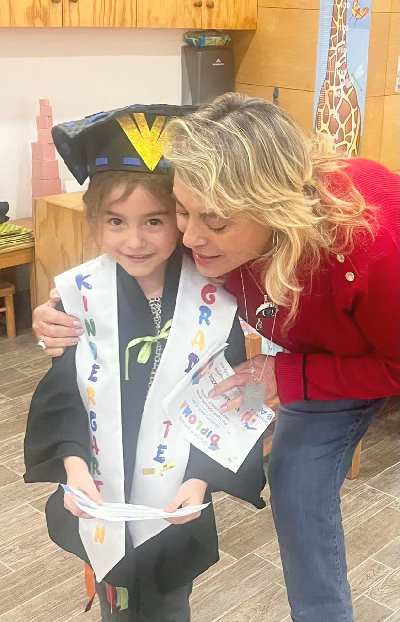 Niña recibiendo su banda de graduación junto a la directora