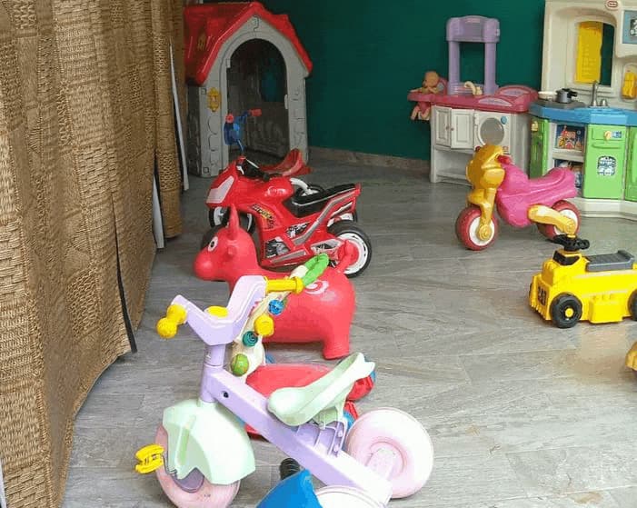 Zona de juego con triciclos, coches de montar, casita y cocinitas
