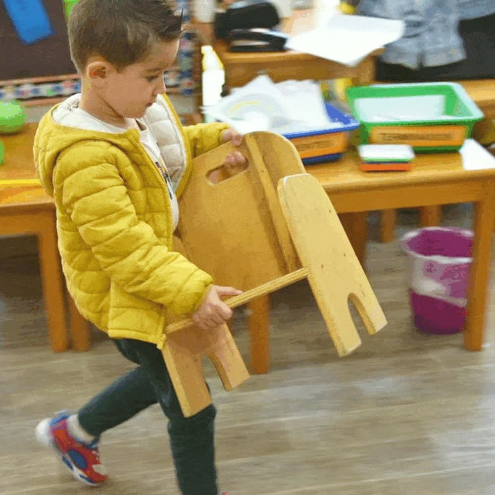 Niño llevando su propia silla por el salón