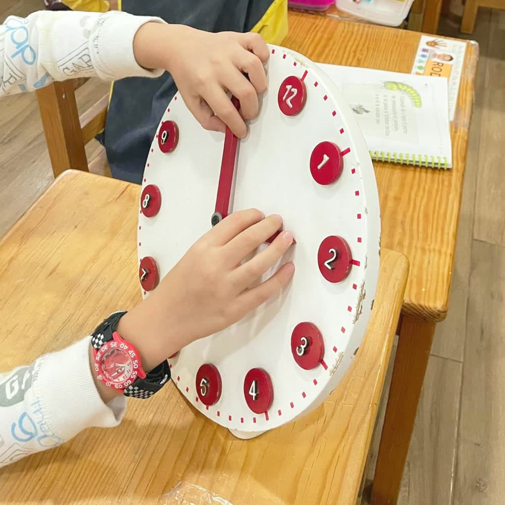 Niña colocando las horas en el reloj de manecillas
